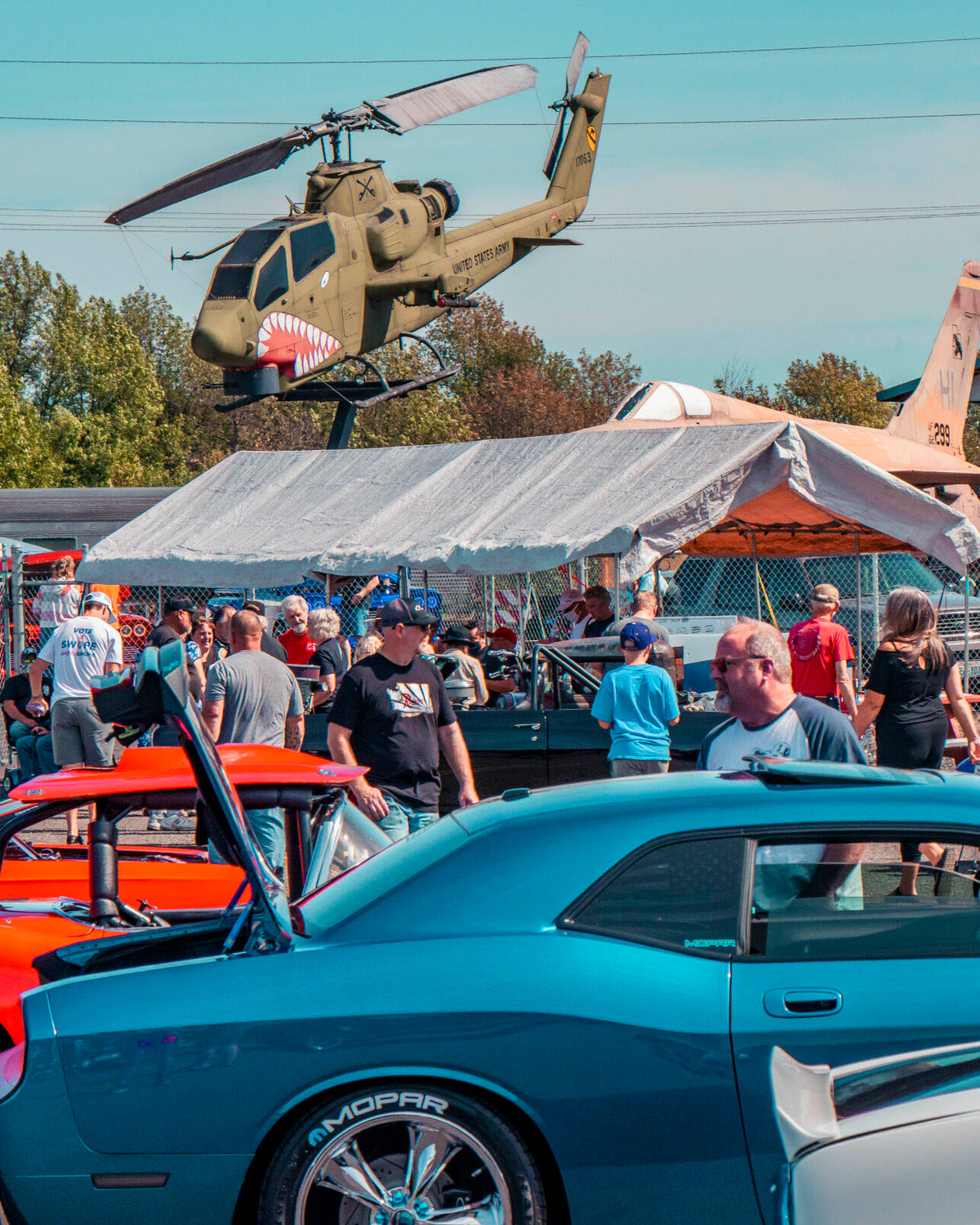A helicopter display is seen above as attendees look at an array of vehicles during a car show hosted by the Veterans Memorial Museum in August 2020.